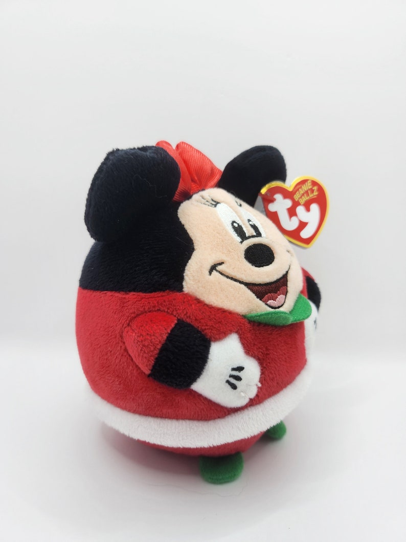 Puede incluir: Juguete de peluche rojo y negro de Minnie Mouse con un traje de Pap&aacute; Noel rojo y blanco con cuello verde. El juguete tiene una etiqueta Ty Beanie Ballz unida a su oreja.