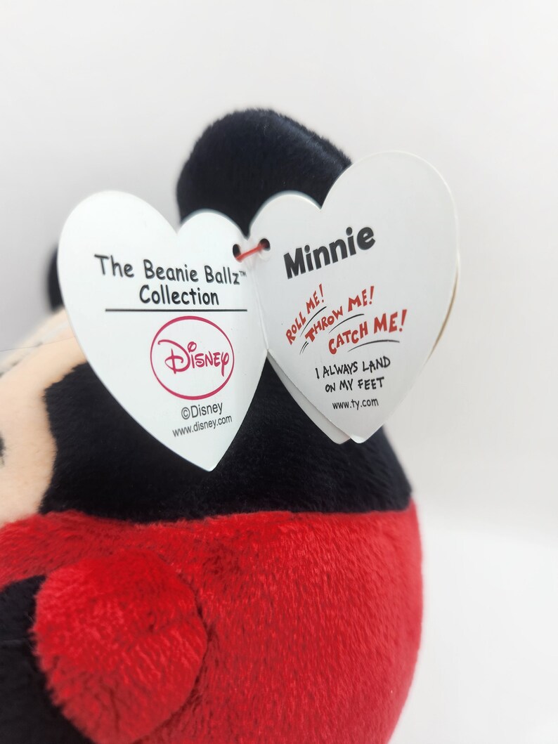 Puede incluir: Un juguete de peluche rojo y negro con forma de Minnie Mouse. El juguete forma parte de la colecci&oacute;n Disney Beanie Ballz. La etiqueta dice "&iexcl;R&oacute;deme! &iexcl;L&aacute;nzame! &iexcl;Atr&aacute;pame! Siempre aterrizo de pie."