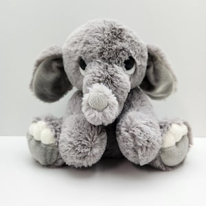 May include: A plush gray elephant toy with large ears, a textured trunk, and white accents on its feet. The stuffed animal has big, dark eyes and a soft, fluffy appearance, perfect for a child's room or nursery.