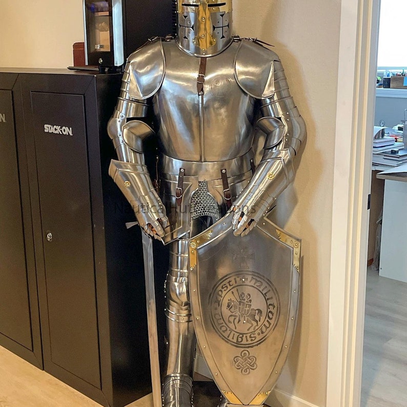 Puede incluir: Un traje de armadura de plata completo con casco, guantes y escudo. El escudo est&aacute; decorado con un dise&ntilde;o dorado y el texto "Zostci 1211 Bis 1216".