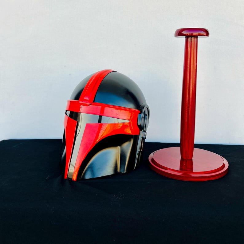 May include: A black and red helmet with a red visor and a red stand. The helmet has a black and red design on the front.