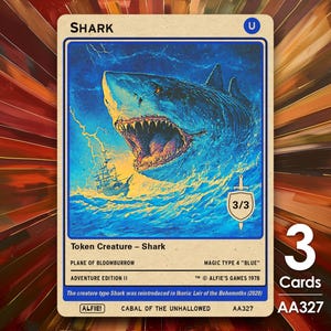 May include: A collectible card with a retro design, depicting a shark in a stormy sea. The card is titled "SHARK" and includes details like "Token Creature" and "Adventure Edition II." The image is accompanied by a label indicating "3 Cards."