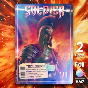May include: A trading card featuring a warrior in armor with the word "SOLDIER" at the top. The card has a holographic foil finish and includes the text "2 Cards" and "1/1". The background is a fiery orange and red.