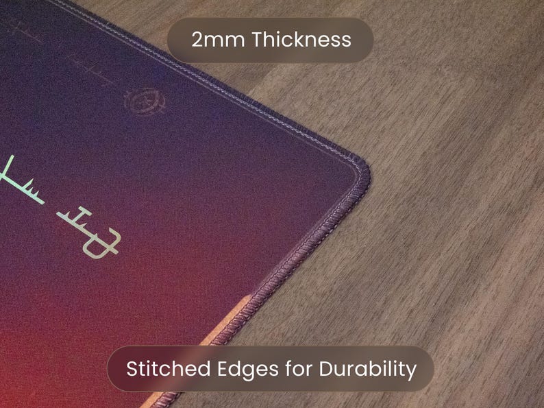 May include: A close-up of a purple and red mousepad with stitched edges for durability. The mousepad is 2mm thick. The mousepad has a design and text in a light green color.
