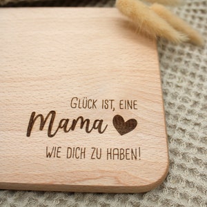 Może przedstawiać: Drewniana deska do krojenia z wygrawerowanym tekstem "Gl&uuml;ck ist, eine Mama wie dich zu haben!" Tekst jest w języku niemieckim i oznacza "Szczęście to mieć mamę taką jak ty!"