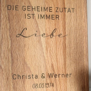 May include: A wooden cutting board with the text "DIE GEHEIME ZUTAT IST IMMER Liebe" and "Christa & Werner 08.03.1974" engraved on it.