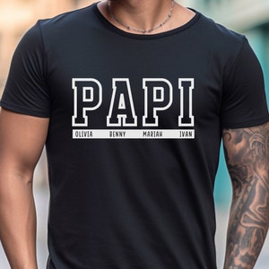 May include: Black t-shirt with the word "PAPI" in white block letters. Below the word are the names "Olivia", "Benny", "Mariah", and "Ivan" in smaller white letters.