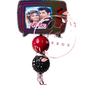 Grease - Rivivi la magia della Rydell High con questo portabadge retrò di Grease!