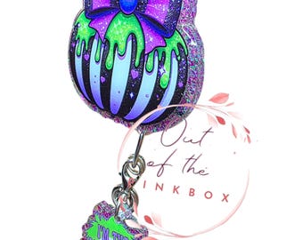 2 inch Halloween Glitter Badge Reel – Purple & Green Dripping Pumpkin with Bow | "I’m the Ghost with the Most Babe" Retractable ID Holder