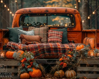 May include: A vintage truck bed decorated for fall with plaid pillows, a blanket, and pumpkins. The truck bed is surrounded by greenery and string lights.