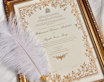 Könnte beinhalten: Eine gerahmte islamische Heiratsurkunde mit goldenen Blumenrändern und Kalligrafie, die die Namen Muhammed Hussein Abubackar und Riyah Iman Razig sowie das Datum 27. Juni 2026 trägt. Ein weißer Federkiel mit goldener Spitze liegt auf dem Dokument.
