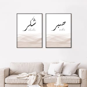 Può includere: Due stampe artistiche incorniciate con cornici nere. Ogni stampa presenta calligrafia araba in inchiostro nero su sfondo bianco. La parte inferiore di ogni stampa presenta un design ad acquerello beige. Le parole "shukr" e "sabr" sono scritte in inglese.