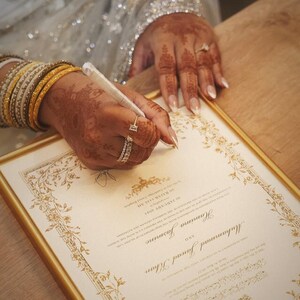 Puede incluir: Un certificado de matrimonio enmarcado con bordes decorativos dorados y texto impreso con los nombres Muhammad Jawad Khan y Hamna Jasmine, fechado el 28 de enero de 2023, 5 de Rajab de 1444 AH, en Cambridge, Reino Unido.