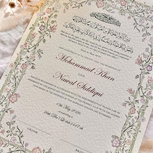Peut inclure: Un certificat de mariage avec une bordure florale et du texte en anglais et en arabe. Il certifie le mariage de Mohammad Khan et Nawal Siddiqui, daté du 13 mai 2026.