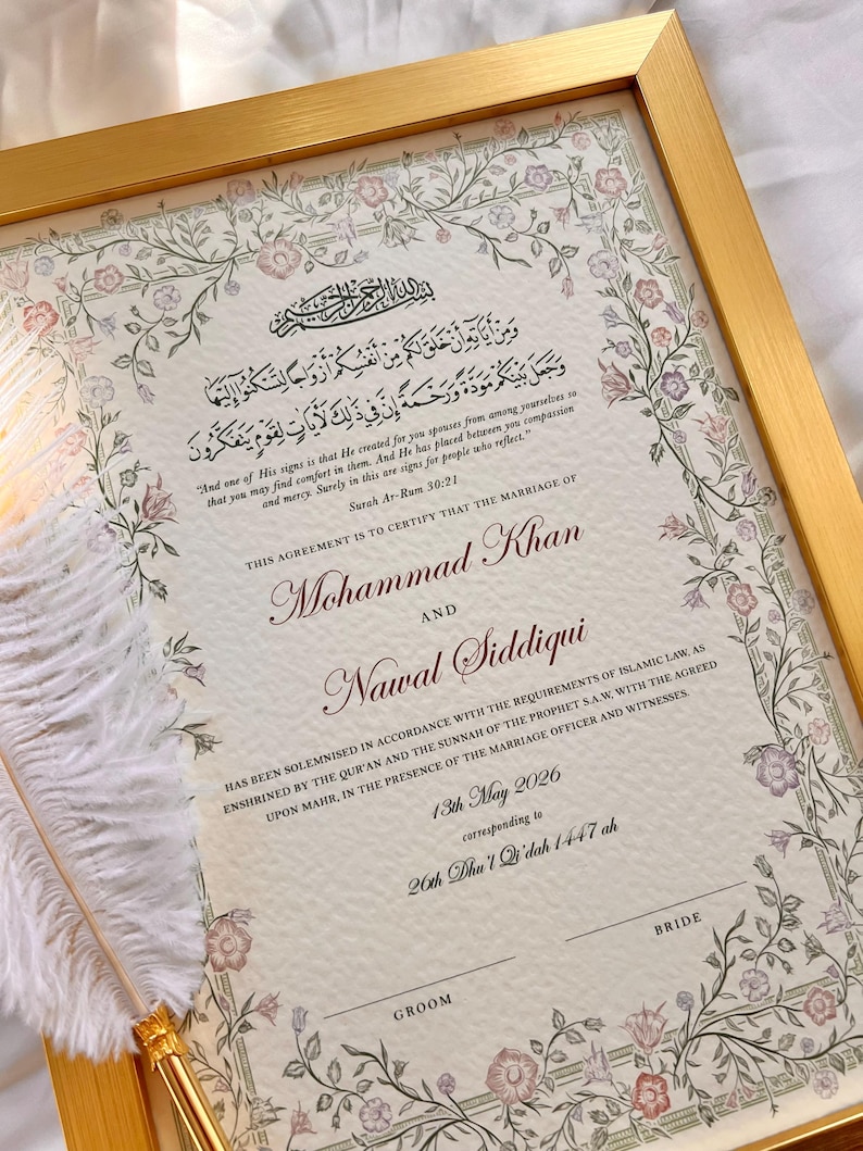 May include: A framed Islamic marriage certificate with a gold border, featuring floral illustrations in pink and green. The document includes Arabic calligraphy, English text, the names Mohammad Khan and Nawal Siddiqui, and a white feather quill pen.