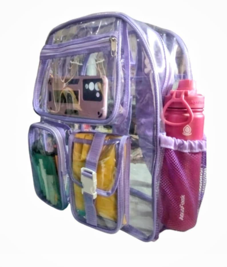 Op de afbeelding: Een transparante paarse rugzak met een zijvak van gaas en een voorvak met ritssluiting. De rugzak heeft een groot hoofdvak en een kleiner voorvak. De rugzak is gevuld met verschillende items, waaronder een waterfles, een telefoon en een notitieboek.