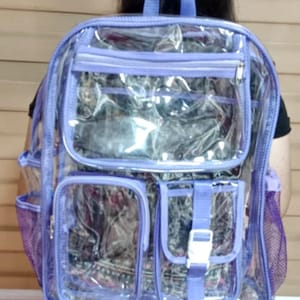 Op de afbeelding: Een transparante rugzak van plastic met paarse afwerking en meerdere vakken. De rugzak heeft een mesh-vak aan de zijkant en een ritsvak aan de voorkant.