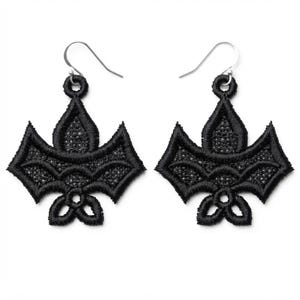 May include: A pair of black embroidered earrings featuring a symmetrical, intricate lace-like design with a pointed top, wide wings, and a three-lobed base. Each earring is attached to a silver-toned metal hook for hanging from the earlobe.