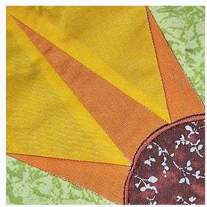 May include: A close-up of a quilt block featuring a sunflower design. The centre of the sunflower is a brown fabric with a white floral pattern. The petals are made of yellow, orange, and green fabric.
