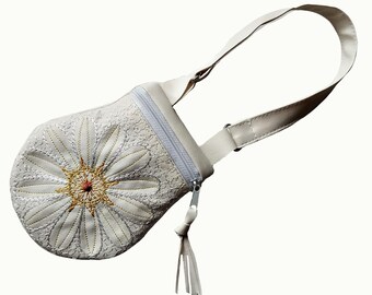May include: A white leather crossbody bag with a floral design embroidered on the front. The bag has a zipper closure and a long adjustable strap.