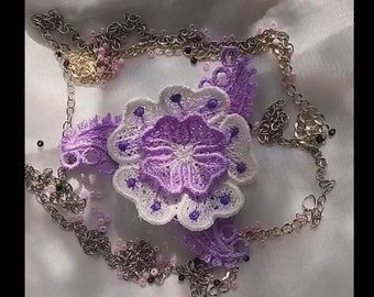 May include: A delicate purple and white lace flower embellishment with a silver chain and beads.