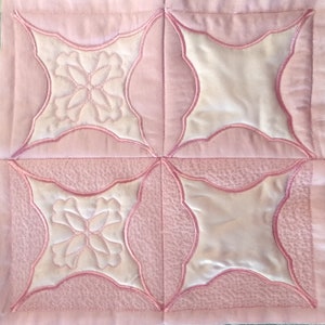 Puede incluir: Una tela acolchada rosa con un patrón repetido de cuatro cuadrados. Cada cuadrado tiene un centro blanco con un diseño floral y un borde rosa.