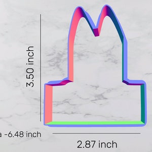 May include: A pink, blue, and green plastic cookie cutter shaped like a bunny rabbit. The cutter is 3.50 inches tall and 2.87 inches wide. Area is 6.48 square inches.