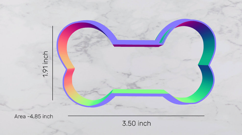 May include: A rainbow-colored plastic dog bone cookie cutter with a 3.50 inch length and 1.91 inch height. The area of the cutter is 4.85 square inches.