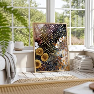 Puede incluir: Una impresi&oacute;n art&iacute;stica floral enmarcada con un dise&ntilde;o abstracto. La obra de arte presenta flores amarillas, blancas y burdeos sobre un fondo oscuro con detalles dorados. La impresi&oacute;n se exhibe en una habitaci&oacute;n luminosa y soleada.