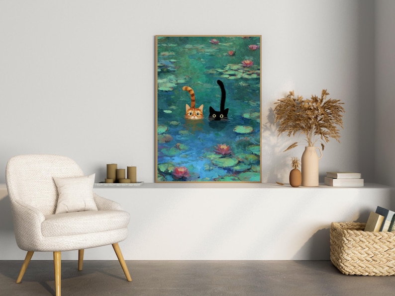 May include: A framed art print showing two cats in a pond with lily pads and flowers. One cat is ginger and white, the other is black. The artwork has a painterly style with a blue and green colour palette.