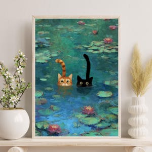May include: A framed art print showing two cats in a pond with lily pads and flowers. One cat is ginger and white, the other is black. The water is blue and green, and the artwork has a painterly style.