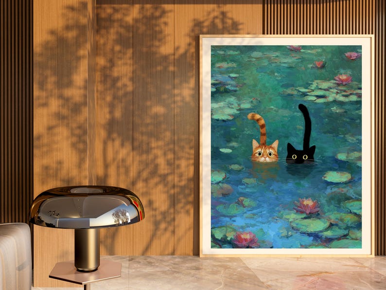 May include: A framed print shows two cats in a pond with lily pads and flowers. One cat is ginger and white, the other is black. The cats are in the water, with only their heads and tails visible. The artwork has a painterly style.