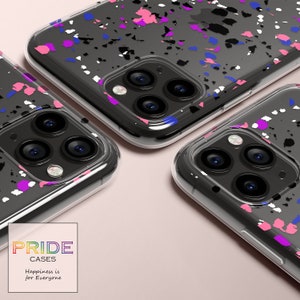 May include: Three clear phone cases with a black, white, pink, blue, and purple splatter paint design. The cases are for an iPhone with a triple lens camera. The text "PRIDE CASES" and "Happiness is for Everyone" is printed on the bottom of the image.