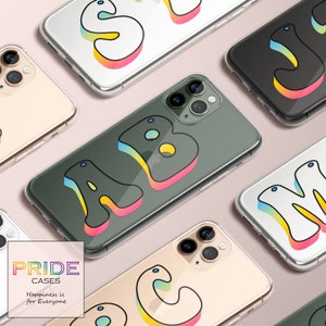 Puede incluir: Un conjunto de seis fundas para teléfono con diferentes letras del alfabeto. Las letras están en un esquema de colores arcoíris y tienen un estilo retro de los años 70. Las fundas son todas transparentes y muestran el teléfono detrás de ellas. El texto en la parte inferior de la imagen dice "PRIDE CASES Happiness is for Everyone".