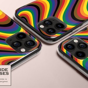 Puede incluir: Fundas transparentes para teléfono con un diseño de remolino arcoíris. Las fundas presentan un patrón vibrante de líneas curvas en varios colores, incluyendo rojo, naranja, amarillo, verde, azul y morado. Las fundas tienen una carcasa de cámara negra. El texto "PRIDE CASES" y "Happiness is for Everyone" es visible.