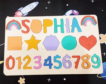 May include: A wooden puzzle board with colorful pieces shaped like letters, numbers, and geometric shapes. The board features the name "SOPHIA" in rainbow colors and numbers 0 through 9.
