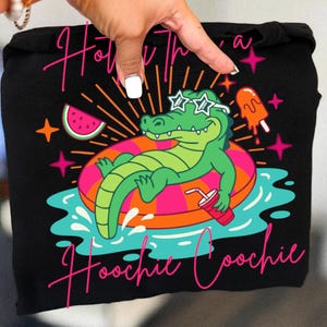 May include: Black tote bag featuring a cartoon alligator wearing sunglasses and floating on an inner tube. The design includes a watermelon slice, popsicle, and the text "How's the Hoochie Coochie?" in pink script.