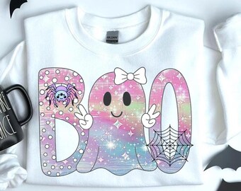 May include: White sweatshirt with a colorful "BOO" graphic. The "B" has a purple spider, the "O" is a ghost with a bow and peace signs, and the other "O" has a spider web. The letters are pastel with glitter.