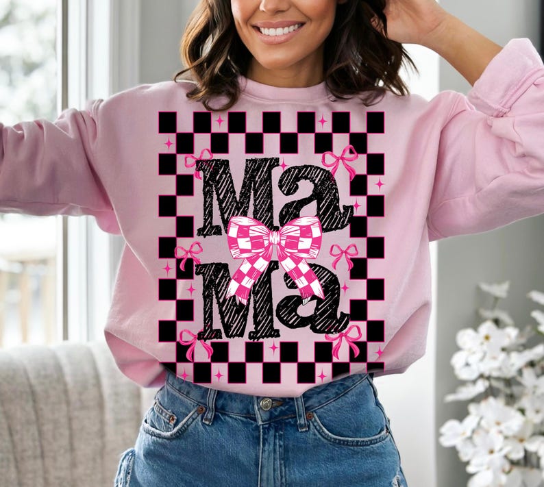 Puede incluir: Sudadera rosa con un patr&oacute;n de cuadros negros y blancos y el texto "Mama" en una fuente de letra negra con lazos rosas.