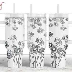 Puede incluir: Tres vasos de acero inoxidable blanco con diseños de margaritas negras y tapas. Cada vaso tiene una pajita negra y un asa.