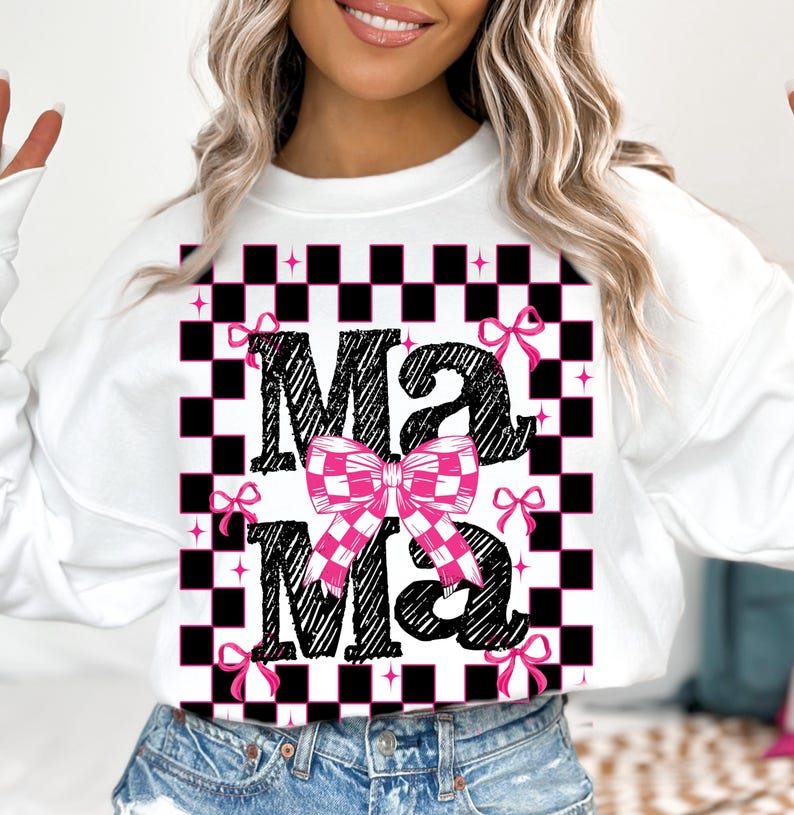 Puede incluir: Sudadera blanca con un patr&oacute;n de cuadros negros y blancos y la palabra "Mama" en negro con un lazo a cuadros rosa y blanco.