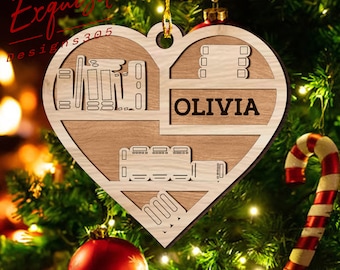 May include: A wooden heart-shaped Christmas ornament with a cutout design. The ornament features a bookshelf with books, a movie reel, and the name "OLIVIA".