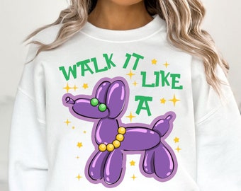 May include: White sweatshirt with a purple balloon animal graphic and the text "Walk it like a..." in green letters.