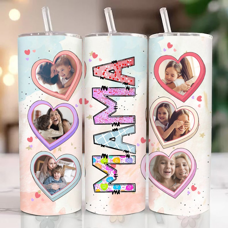 Op de afbeelding: Drie roestvrijstalen bekers met roze, blauwe en witte ontwerpen. Elke beker heeft een hartvormig frame met een foto van een moeder en een kind. De middelste beker heeft het woord "MAMA" in roze glitterletters geschreven.