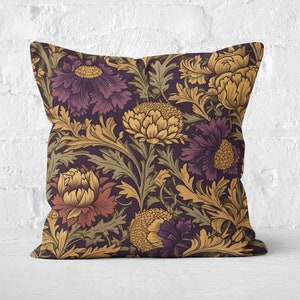 May include: Square cushion with a floral design. The pattern showcases large, stylized flowers in purple, gold, and rust hues on a dark backdrop. The cushion is placed on a white surface in front of a white brick wall.