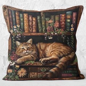 Op de afbeelding: Een bruine en oranje tabbykat slaapt op een boekenplank vol boeken. De boekenplank is versierd met bloemen en groen. De kat ligt op zijn zij met zijn kop op zijn poten.
