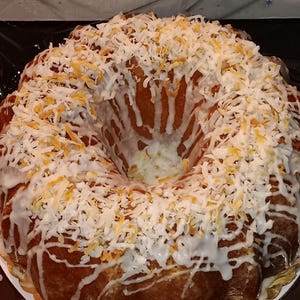 May include: A white bundt cake with a white glaze and shredded coconut on top.