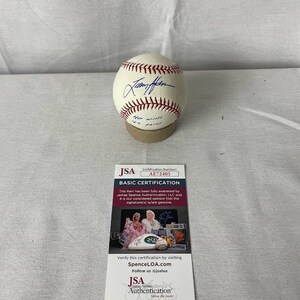 May include: A white baseball signed by "Jammy Foxx" with the text "449 wins 449 saves" on the ball. The baseball is on a brown base. The baseball is authenticated by JSA with the certification number AE72405.