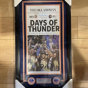 Puede incluir: Impresión enmarcada del periódico The Oklahoman, conmemorando las Finales de la NBA de 2025. El titular dice "DAYS OF THUNDER" con el logotipo de los Oklahoma City Thunder. El marco es negro con borde azul, la impresión muestra al equipo celebrando.