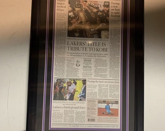May include: A framed Los Angeles Times newspaper article commemorating the Los Angeles Lakers' 2020 NBA Championship. The headline reads "LAKERS' TITLE IS TRIBUTE TO KOBE". The article features a photo of the Lakers celebrating their victory. The frame includes two Lakers logos.